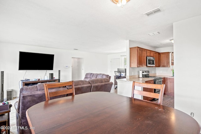 dining space with a textured ceiling, visible vents, and wood finished floors