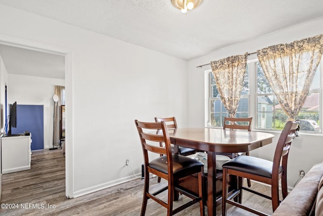 dining area featuring a textured ceiling, baseboards, and wood finished floors