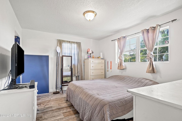 bedroom with light wood-style floors and a textured ceiling