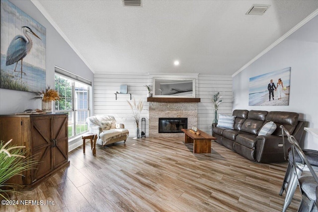 living room with a fireplace, crown molding, lofted ceiling, and wood-type flooring