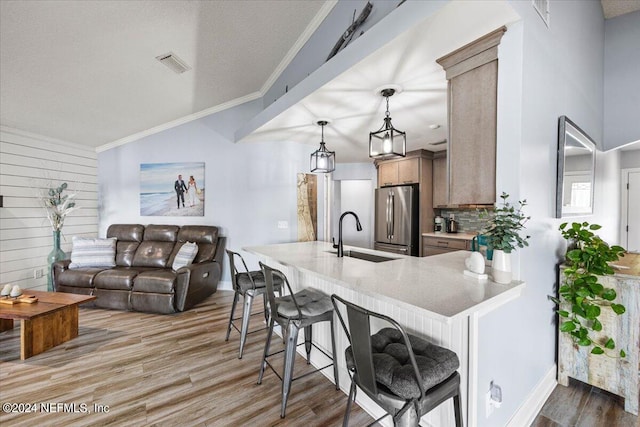 kitchen featuring hardwood / wood-style floors, kitchen peninsula, stainless steel refrigerator, and sink