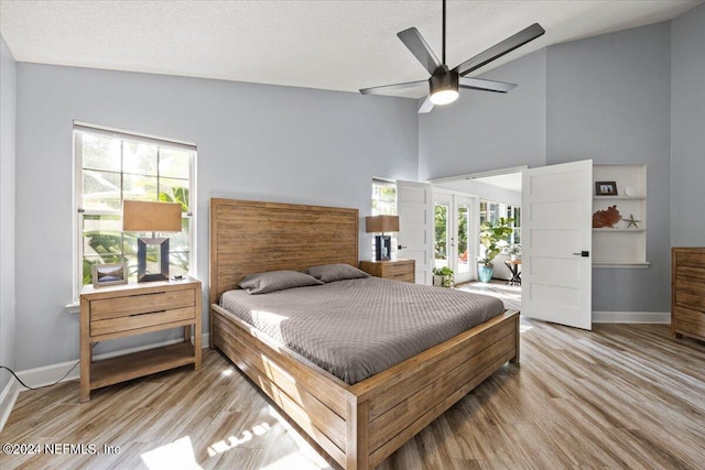 bedroom featuring high vaulted ceiling, ceiling fan, a textured ceiling, and light hardwood / wood-style flooring