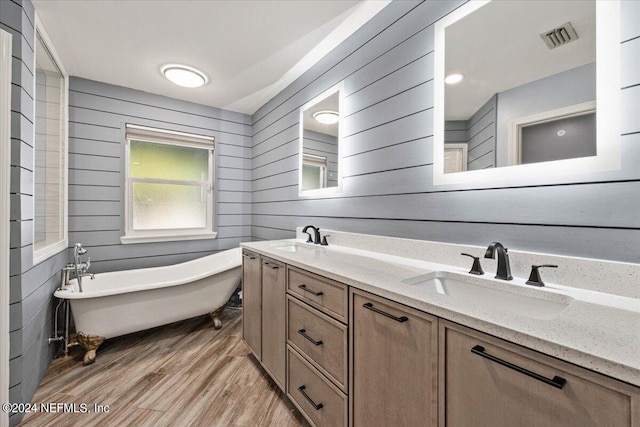 bathroom featuring a tub to relax in, vanity, wood-type flooring, and wooden walls