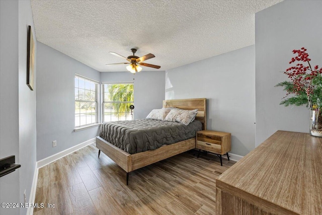 bedroom featuring ceiling fan, a textured ceiling, and light hardwood / wood-style flooring