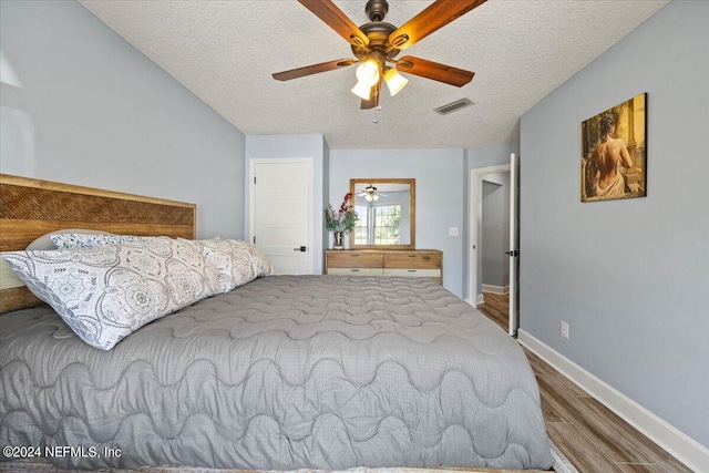 bedroom with ceiling fan, hardwood / wood-style flooring, and a textured ceiling