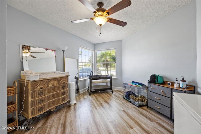 bedroom with a textured ceiling, ceiling fan, and light hardwood / wood-style floors