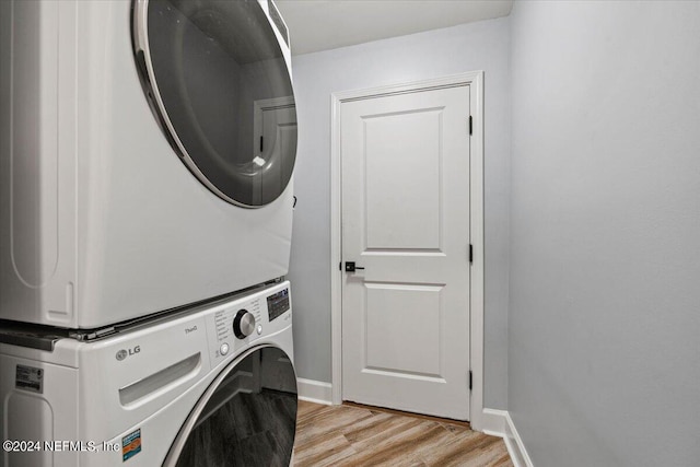 laundry area with stacked washer and dryer and light hardwood / wood-style floors