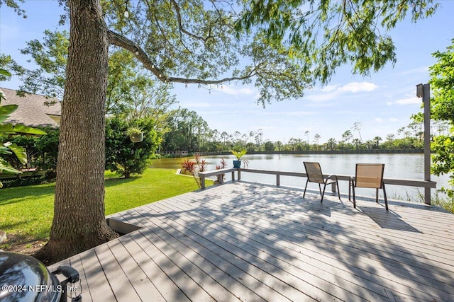 view of dock with a yard and a deck with water view