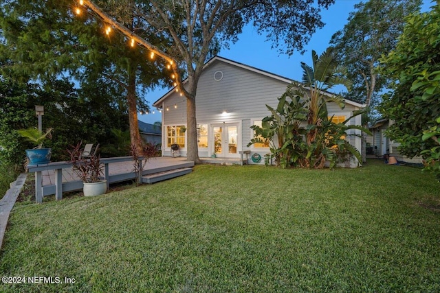 rear view of property featuring a lawn, a deck, and french doors