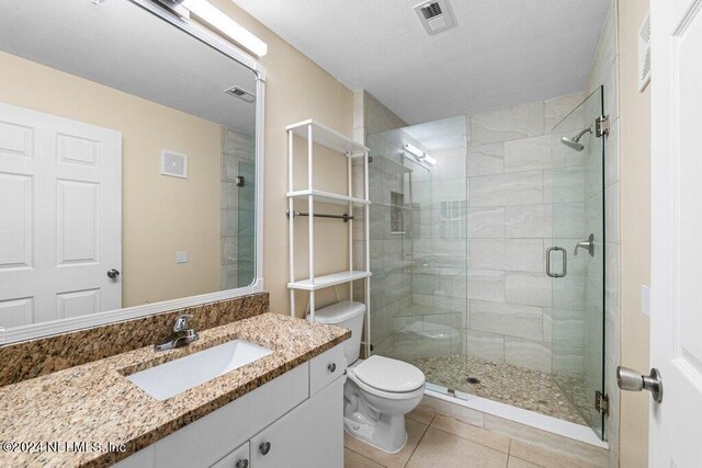 bathroom with tile patterned flooring, a shower with door, vanity, and toilet