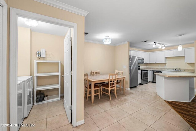 kitchen with light tile patterned flooring, white cabinetry, stainless steel appliances, independent washer and dryer, and ornamental molding