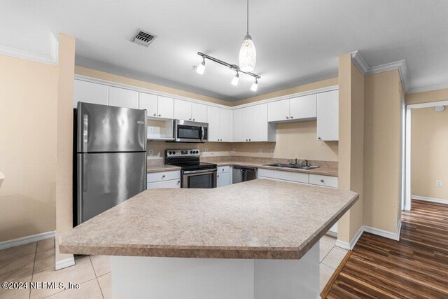 kitchen with decorative light fixtures, stainless steel appliances, light hardwood / wood-style floors, and white cabinetry