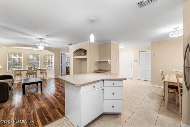 kitchen featuring light hardwood / wood-style floors, white cabinets, decorative light fixtures, ornamental molding, and ceiling fan