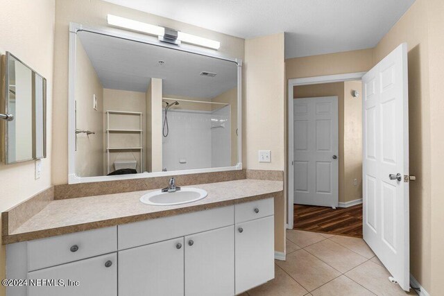 bathroom featuring walk in shower, vanity, and hardwood / wood-style floors