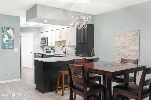 dining area with sink, an inviting chandelier, and light hardwood / wood-style floors