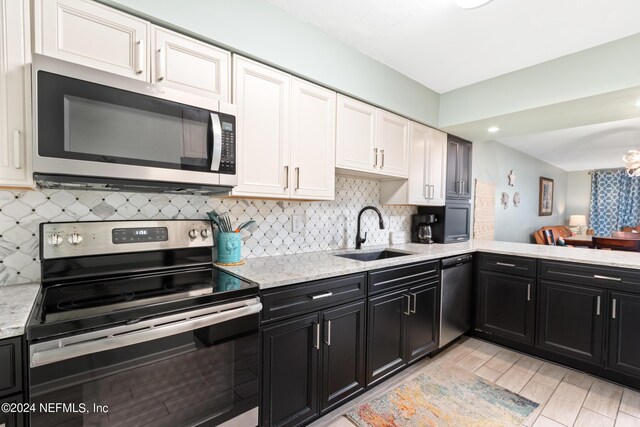 kitchen with backsplash, sink, appliances with stainless steel finishes, and white cabinetry