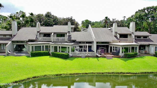 back of property featuring a lawn, a water view, and a balcony