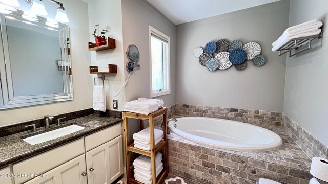 bathroom with tiled tub and vanity