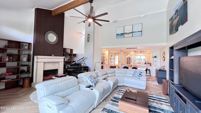 living room with a towering ceiling, ceiling fan, light parquet flooring, and a fireplace