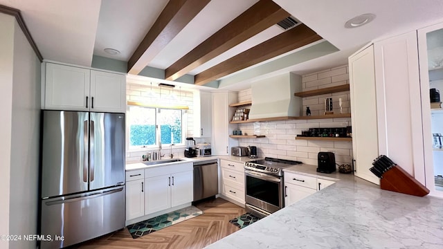 kitchen featuring decorative backsplash, white cabinets, stainless steel appliances, premium range hood, and sink