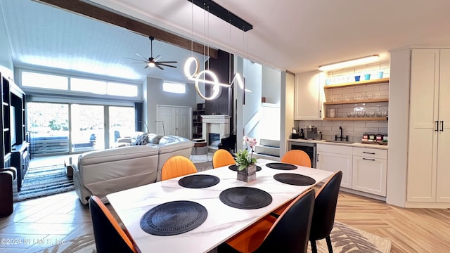 kitchen featuring ceiling fan, white cabinets, hanging light fixtures, sink, and light parquet floors