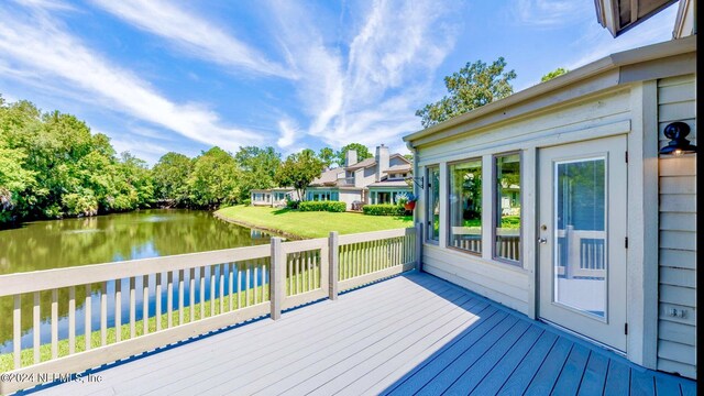 wooden deck featuring a lawn and a water view