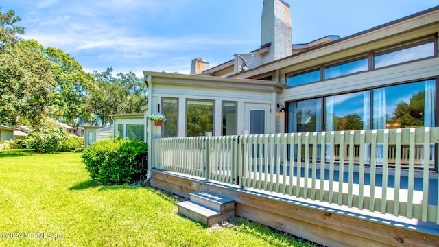 back of property with a wooden deck and a yard