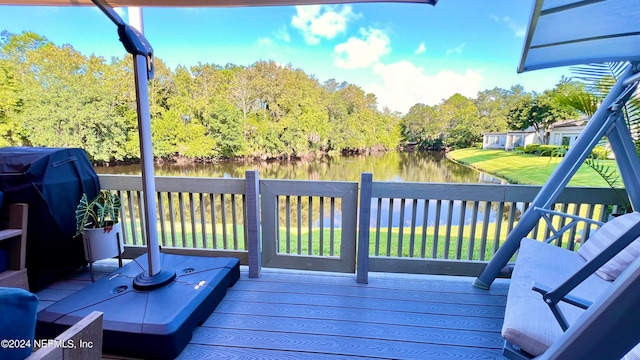 deck with grilling area, a lawn, and a water view