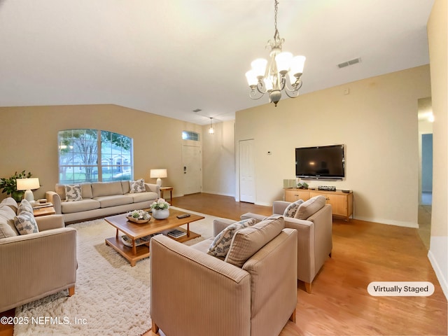 living room with a chandelier, light hardwood / wood-style floors, and vaulted ceiling