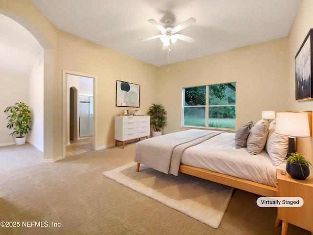 bedroom with arched walkways, baseboards, ensuite bath, and carpet