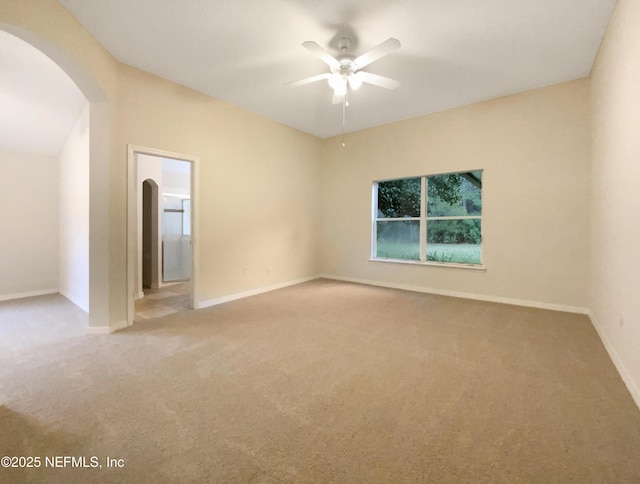 empty room with baseboards, arched walkways, light carpet, and a ceiling fan