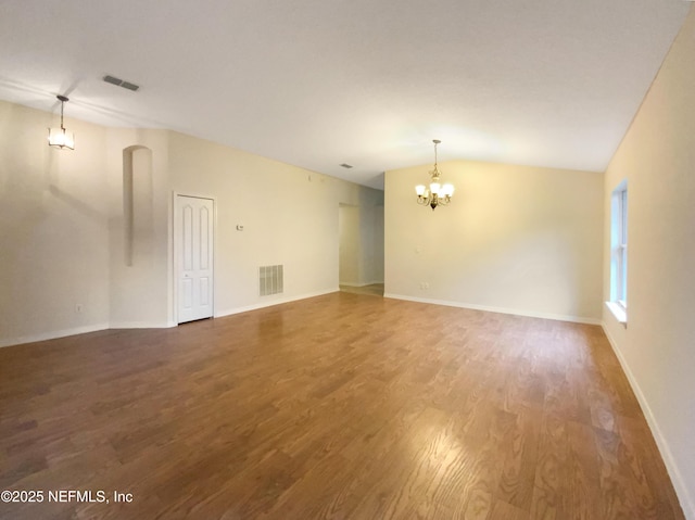 empty room with visible vents, baseboards, a chandelier, vaulted ceiling, and wood finished floors