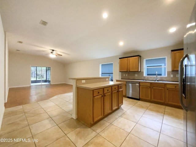 kitchen with a kitchen island, stainless steel appliances, brown cabinetry, decorative backsplash, and vaulted ceiling