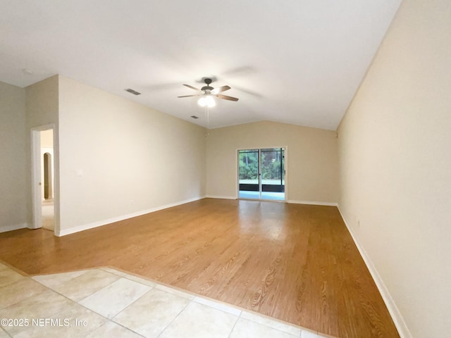 empty room featuring light wood-type flooring, visible vents, baseboards, ceiling fan, and vaulted ceiling