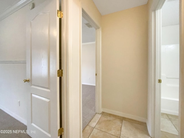 hallway with tile patterned floors, visible vents, and baseboards