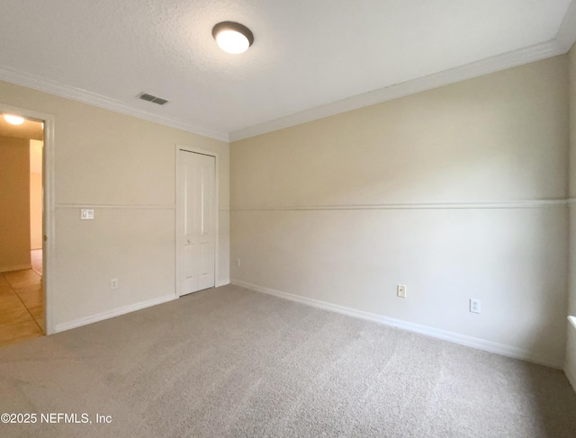 unfurnished bedroom featuring carpet, visible vents, baseboards, a closet, and crown molding