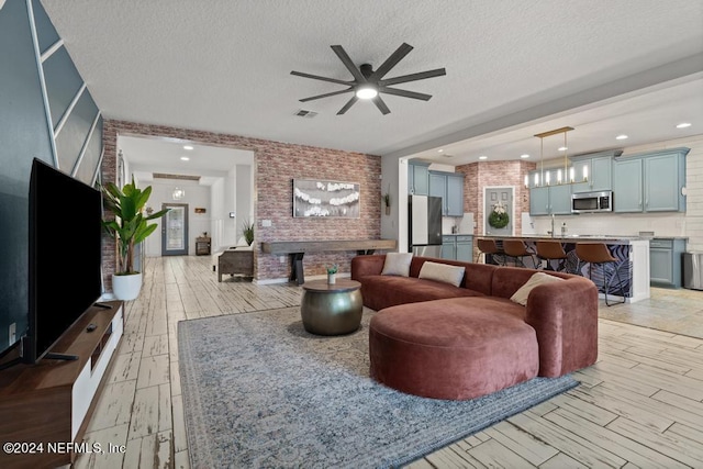 living room with a textured ceiling, light hardwood / wood-style flooring, and ceiling fan