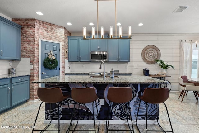 kitchen featuring a kitchen breakfast bar, a center island with sink, and blue cabinetry