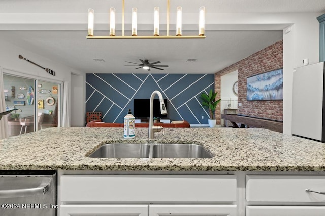 kitchen with ceiling fan, sink, light stone countertops, and white cabinets