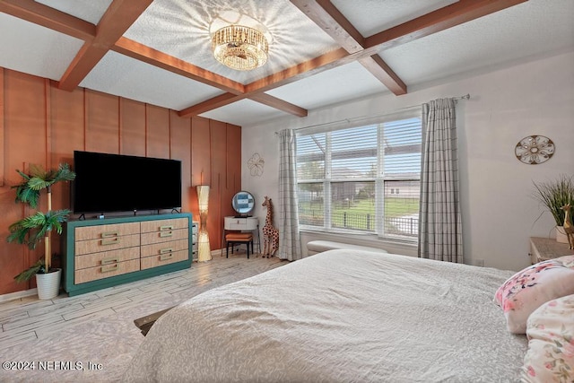 bedroom with beamed ceiling, coffered ceiling, light hardwood / wood-style floors, and a notable chandelier