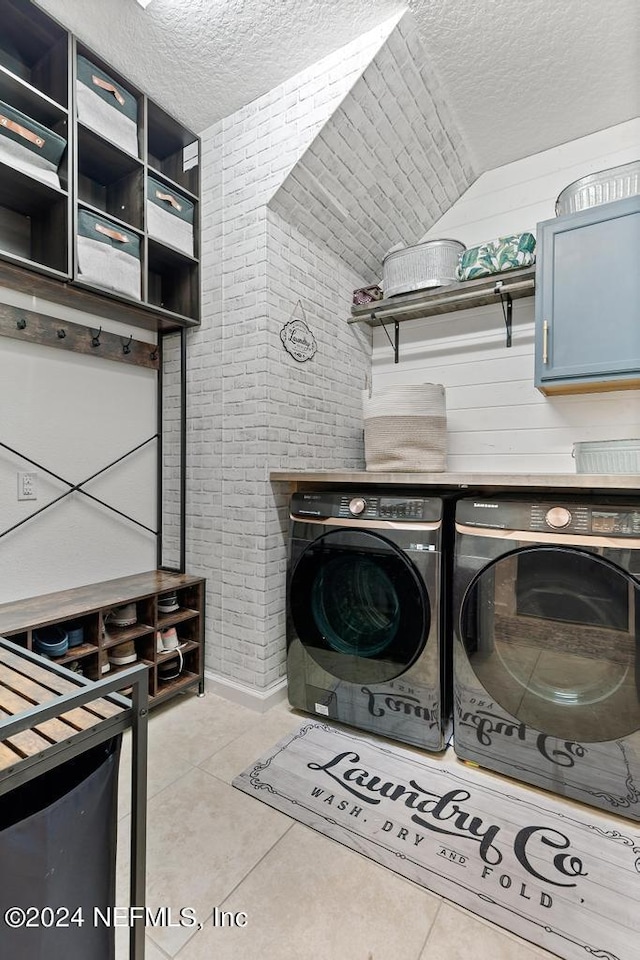 laundry room featuring light tile patterned floors, a textured ceiling, cabinets, and washer and dryer