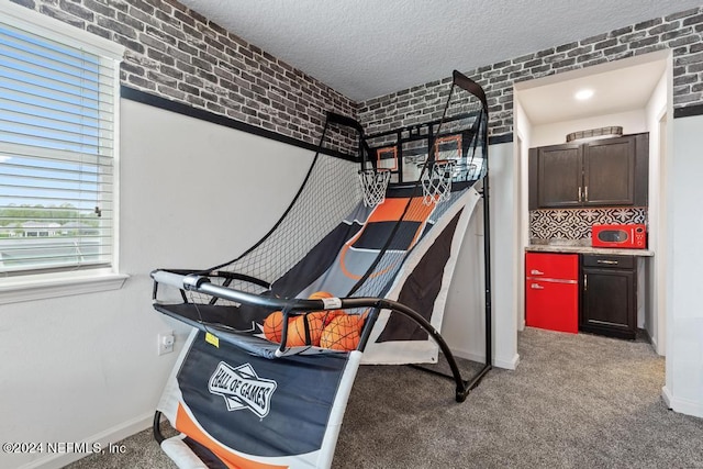 carpeted bedroom with a textured ceiling and brick wall