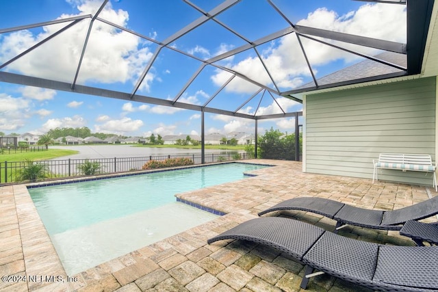 view of swimming pool featuring glass enclosure, a patio area, and a water view