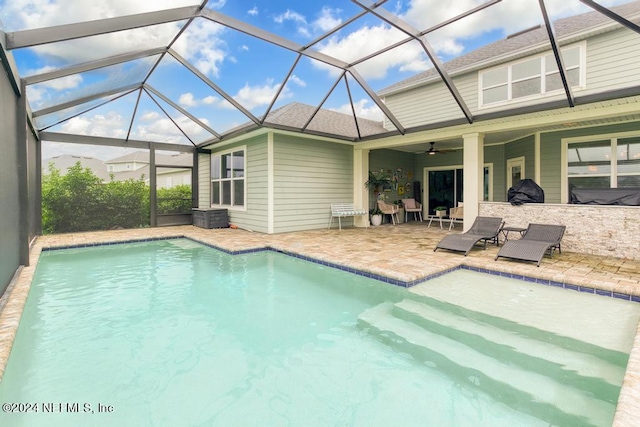 view of pool featuring glass enclosure, a patio area, and ceiling fan