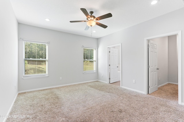 unfurnished bedroom with ceiling fan, light colored carpet, and a walk in closet