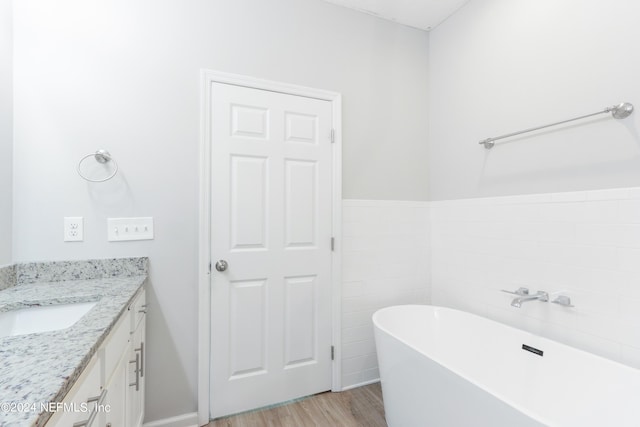 bathroom featuring a tub to relax in, tile walls, vanity, and wood-type flooring