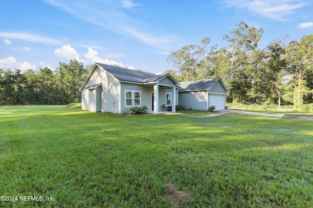 view of front of house featuring a garage, a front lawn, and an outbuilding