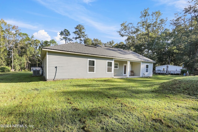 rear view of property featuring central AC and a lawn