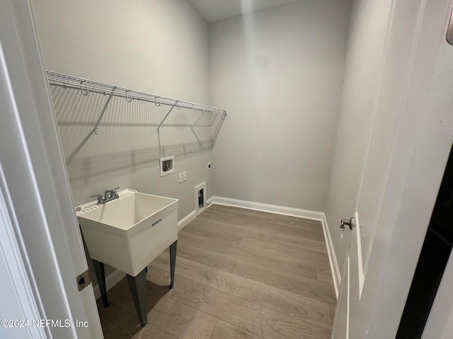 washroom featuring hookup for a washing machine, electric dryer hookup, and light hardwood / wood-style flooring