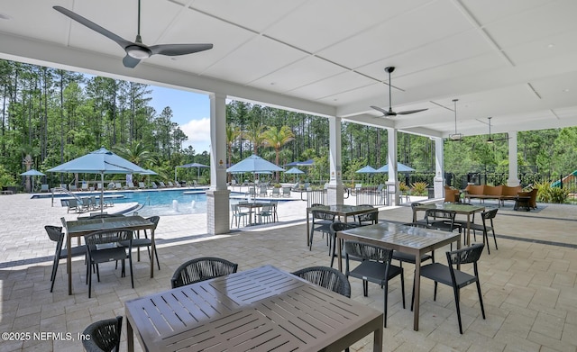 view of patio with a community pool and ceiling fan